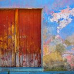 red wooden door of blue, red, and brown painted wall